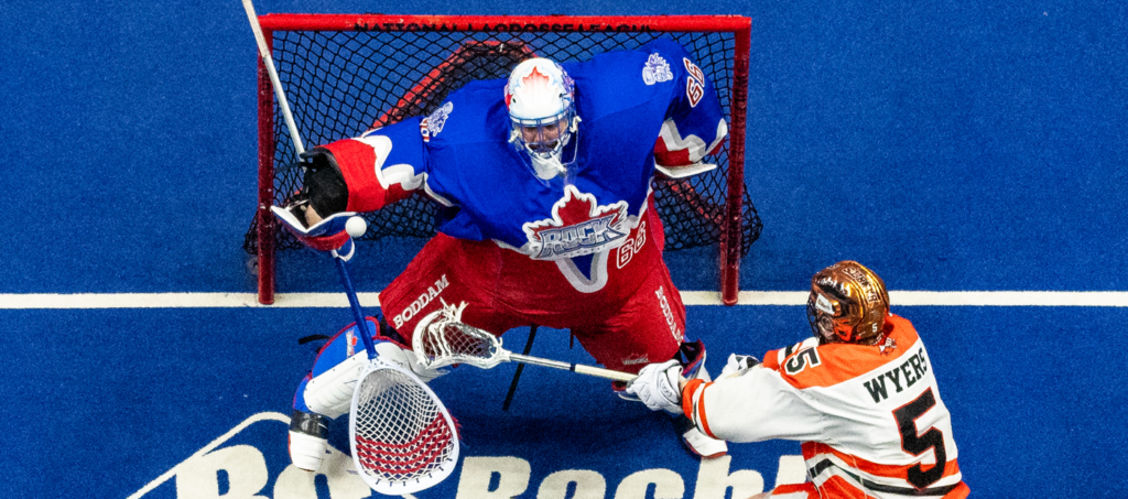 Lacrosse goalie makes a save while a player attempts a shot during a game.